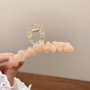 Dettaglio della pinza per capelli a forma di cuore con accenti rosa opaco e molla dorata