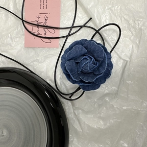 Vue détaillée d'un collier fleur de camélia en denim bleu foncé avec lien à nouer noir