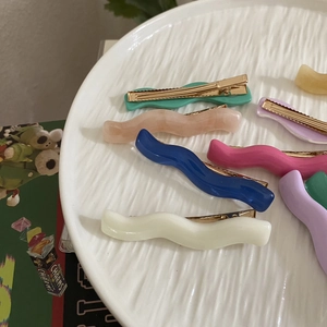 Colorful wave acrylic hair clips in various macaron shades on a ceramic plate