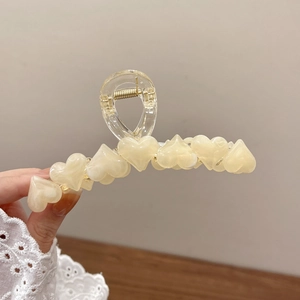 Dettaglio di un grande fermaglio per capelli a cuore crema con perle di resina 3D