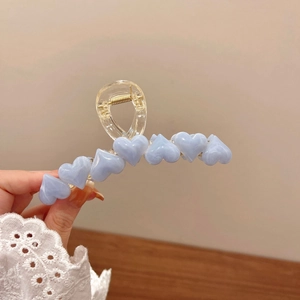 Dettaglio di molletta trasparente con cuori blu marmorizzati e molla in metallo oro
