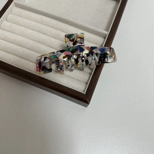 Detail of artistic acetate hair claw clip with colorful oil painting pattern and gold text