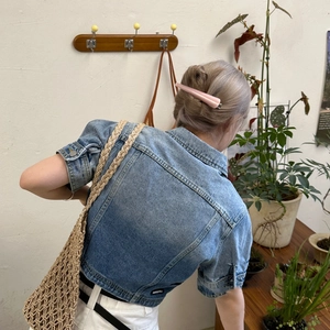 Pale pink acetate hair clip worn on a low ponytail in a natural lifestyle setting