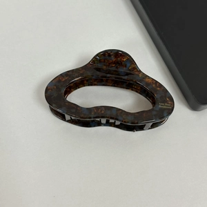 Macro detail of tortoiseshell acetate claw clip with blue flecks and gold handmade script