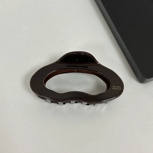 Detailed close-up of dark brown glossy claw clip with Amy Bear golden text