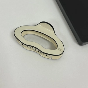 Detail view of cloud-shaped acetate hair claw with black border and handmade engraving