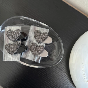 Elegant rhinestone heart hair clips in black and cream sets on a wooden display