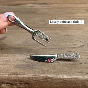 Quirky silver cutlery hair clips with sparkling rhinestones and pink gems on wood