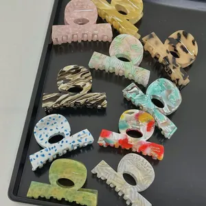 Assorted acetate hair claw clips with leopard print and marble textures on a tray