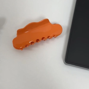 Detail of glossy orange wavy cloud hair claw clip with dense teeth for thick hair