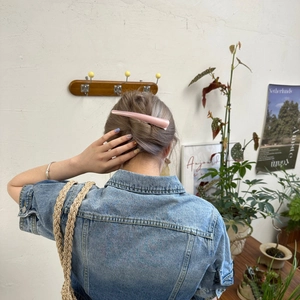 Detail view of a pink matte acetate hair clip worn on a model in a minimal setting