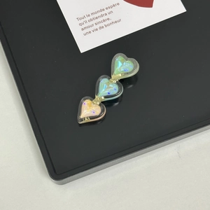 Close-up of triple heart hair clips with holographic gradient effect on a display tray