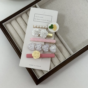Close-up of five-piece hair clip set with pearls and resin flowers on display card