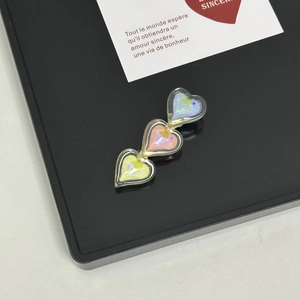 Detailed view of three heart-shaped crystals in blue, pink, and yellow on a hair clip