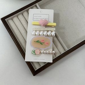 Detail view of 5-piece hair clip set with cream pearls, tulips, and heart designs