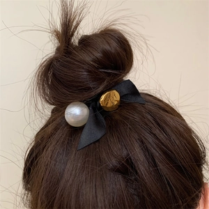 French vintage hair scrunchie with black ribbon bow, pearl, and gold charm on bun