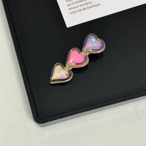 Macro shot of three interconnected pastel glitter heart hair clips on black display board