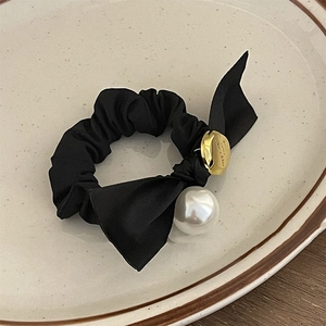 French vintage black bow hair tie with large pearl and gold charm on a ceramic tray
