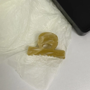 Close-up of amber acetate hair claw clip with Barrette la France logo on white paper