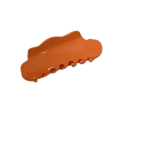 Oversized cloud-style orange acetate hair claw clip with wave edges and glossy finish