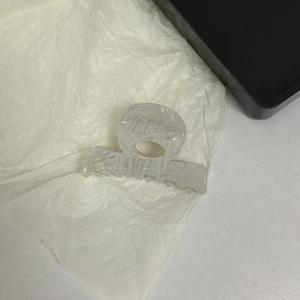 Detail view of white marble acetate hair claw clip with grey ink pattern on paper background