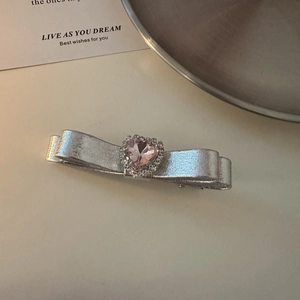 Macro view of silver ribbon bow hair clip with pink heart-shaped crystal and small rhinestones