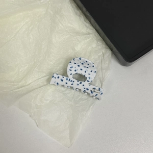 Detail of white acetate hair claw with blue dots and gold Barrette la France logo