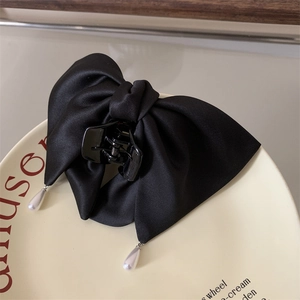 Pince à cheveux élégante en satin noir avec perles pendantes sur une assiette en céramique