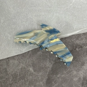Détail de la grande pince à cheveux en acétate avec motif marbre bleu et logo doré