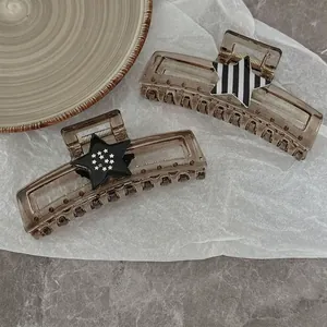 Large star-shaped amber hair claw clips with striped and sparkly patterns on marble