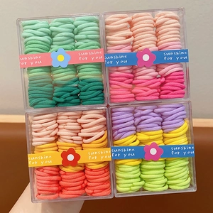 Close-up of candy-colored elastic hair ties in clear acrylic boxes for girls' hairstyling