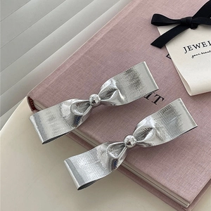 Barrettes à cheveux nœud argenté avec texture métallique sur un livre rose