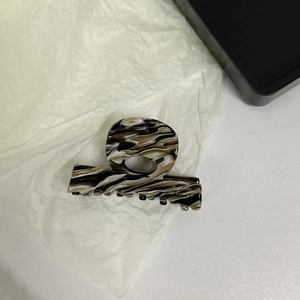 Close-up of marble acetate hair claw clip with golden Barrette la France logo
