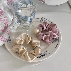 Détail de chouchous en satin avec perles en champagne et rose poudré aspect soie