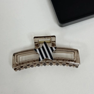 Close-up of a brownish star hair claw clip with a black and white striped star design