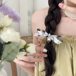 Barrette à cheveux nœud argenté avec pendentif cœur sur une coiffure tresse noire