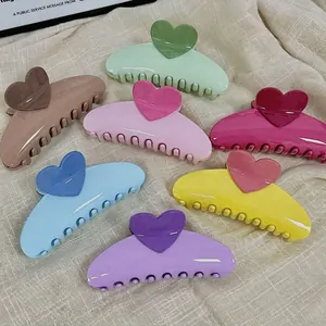 Colorful heart-shaped hair claw clips in cream tones on a beige textured cloth background