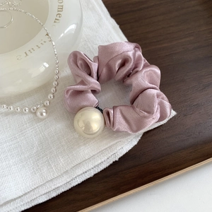 Vue rapprochée du chouchou en satin rose pâle orné d'une grande perle brillante