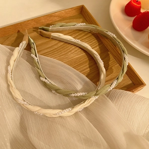 Green and cream twisted pearl headbands on a wooden tray with a vintage aesthetic look