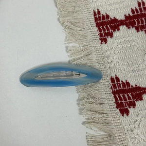 Close-up of a blue oval acetate barrette with silver metal clip and engraved text