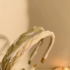 Detail of twisted fabric headband with embedded pearls in green and cream tones