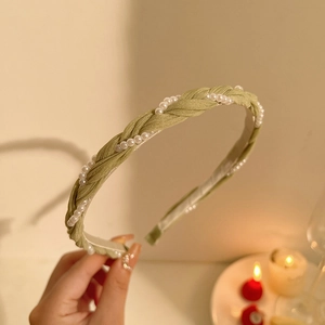 Detailed view of green braided headband with white pearl accents for a vintage look
