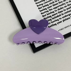 Macro detail of glossy light purple heart claw clip with smooth polished finish and teeth