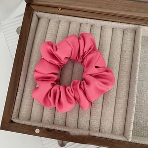 Dettaglio di un elastico in raso rosa esposto in una scatola per gioielli in legno scuro