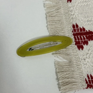 Macro detail of oval acetate hair clip in lime green with durable metal spring fastener