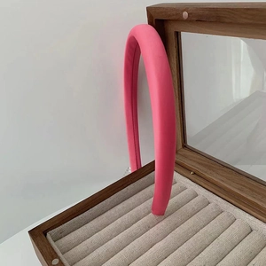 Dettaglio ravvicinato di una fascia per capelli imbottita in tessuto rosa in un portagioie