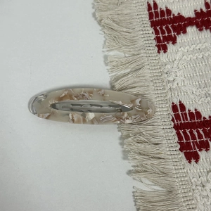 Macro shot of oval acetate hair clip with marble pattern and silver metal spring clip