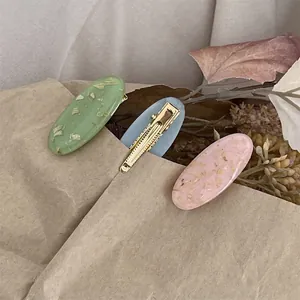 Trois barrettes ovales pastel avec feuille d'or sur fond de papier kraft texturé