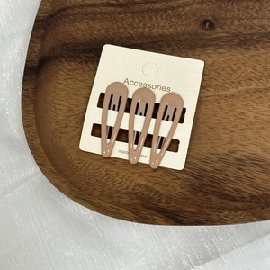 Vue détaillée de trois pinces à cheveux crème présentées sur une carte cadeau