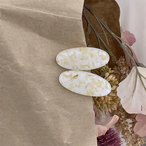 Vue détaillée de barrettes ovales en résine avec fleurs séchées jaunes et style vintage
